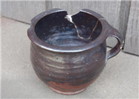 This is a Tudor chamber pot made of blackware.